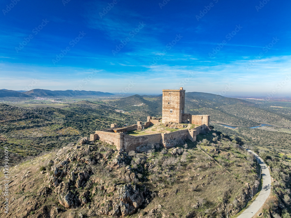 Aerial view of Feria castle in Spain, Gothic and Mudéjar style buildings, square keep, blue sky background
