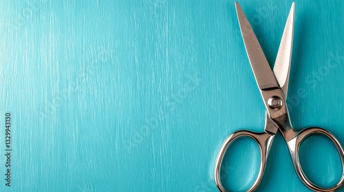  a pair of scissors sitting on top of a blue surface The scissors are silver in color and have a curved handle with a pointed tip The blue surface is smooth and gl photo