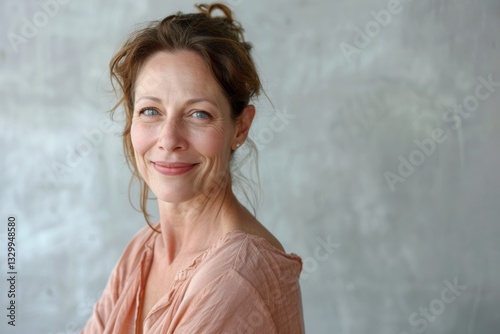 Portrait of a content caucasian woman in her 40s smiling at the camera in minimalist or empty room background