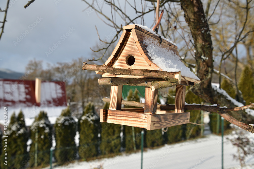 Handmade wooden birdhouse hanging on a tree branch in winter