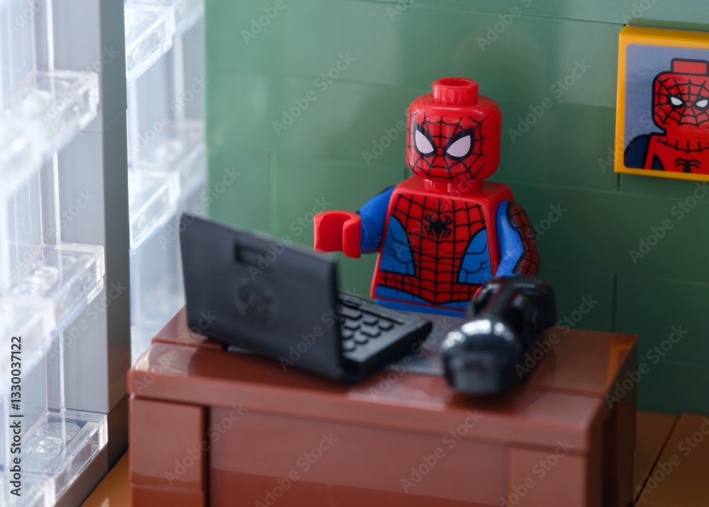 Fototapeta premium Tambov, Russian Federation - February 12, 2025 Lego Spider-Man minifigure working behind a laptop on his workplace at the office