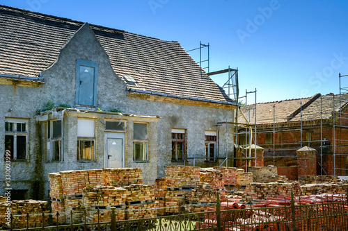 Restoration of an old farmhouse. In the garden are new roof tiles for the repair of the roof and the old bricks of the facade.