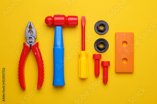Set of children's toy tools on a yellow background. Flat lay