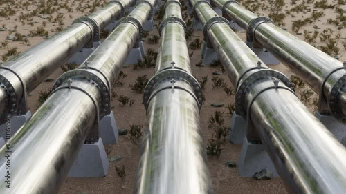 Close-up view of multiple industrial pipelines transporting oil or gas through a dry, rugged landscape.