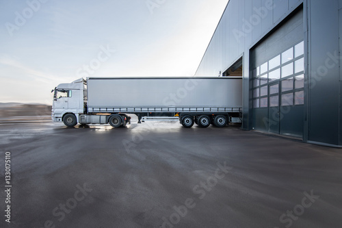 A large white semi truck is parked in front of a building