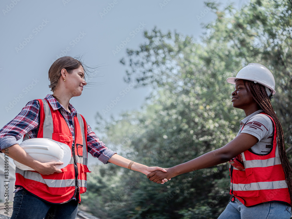 Female architectural engineer with civil planner assistant and inspector before working on rail transport project at construction site. Handshake for successful concept.