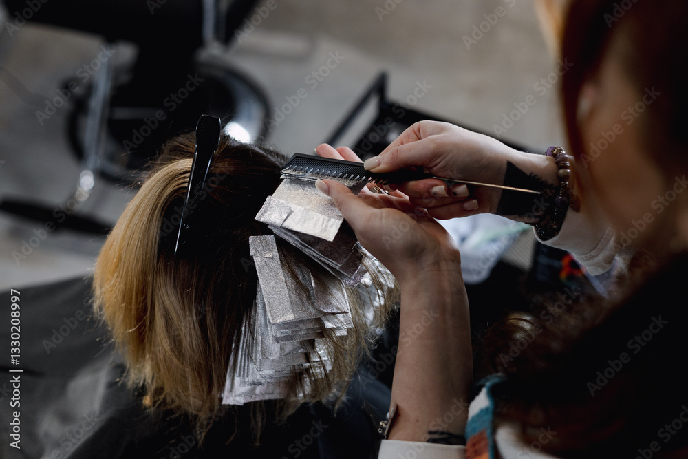 Fototapeta premium A professional hairstylist blow-drying and styling a client’s blonde hair in a modern salon setting.
