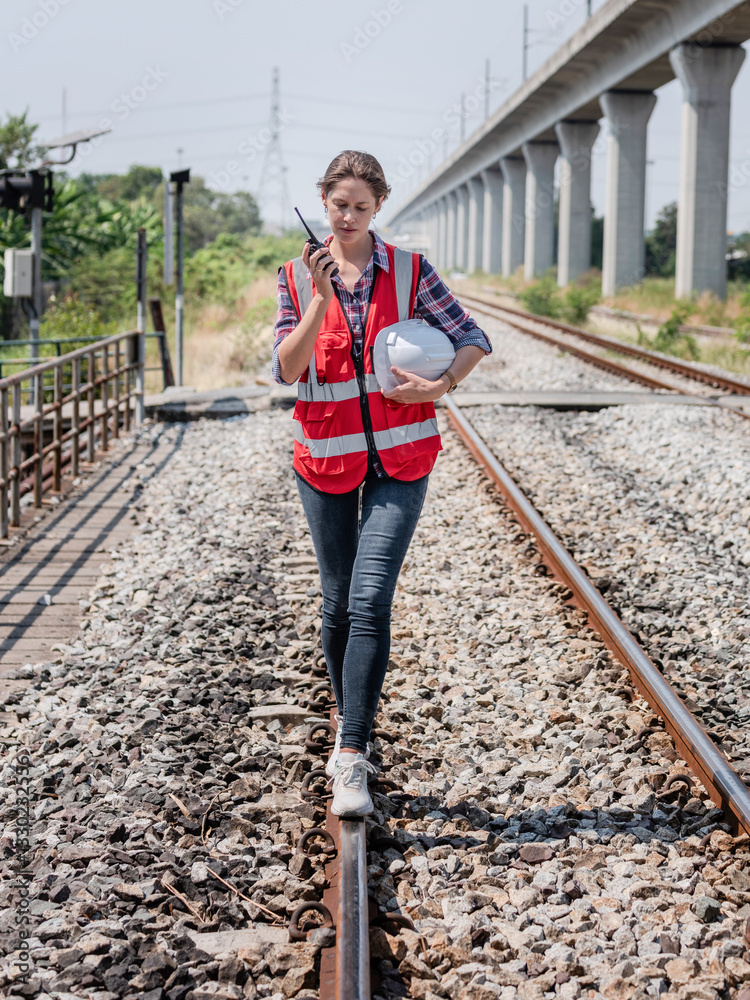 Engineer is walking to inspect the railway track, walking on the railway, looking happy at work while inspecting the construction, train switch and inspecting.