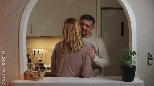 Loving couple hugging, whispering softly near kitchen counter, expressing tender connection through gentle closeness and warm embrace