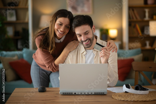 Wallpaper Mural Couple using laptope to buy online. Man holding credit card to pay bills online Torontodigital.ca