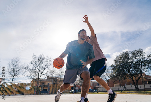 Basketball players competing on outdoor court: intense match between friends