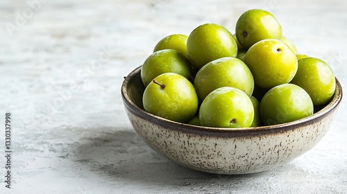 Fresh ripe organic green plums or greengage in bowl on white rustic background, heap of summer fruits concept 