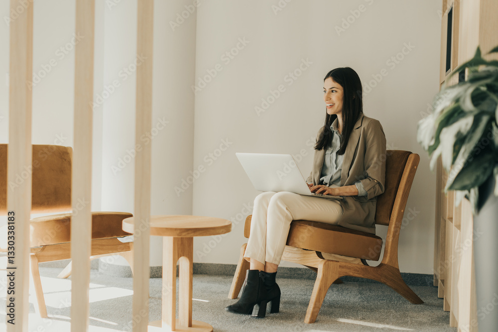 Young woman working on laptop in a modern office setting with stylish furniture and natural light Young woman working on laptop in a modern office setting with stylish furniture and natural light