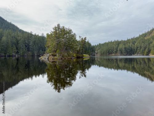 Small island in the middle of a calm lake surrounded by trees