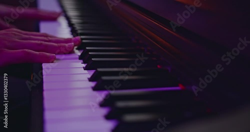Piano keys played with purple lighting, creating a moody and artistic atmosphere. Ideal for music production, composition, or performance.