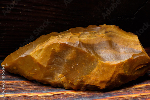 A flint spearhead with exquisite retouching on a wooden background, a relic from the Stone Age, found in central Russia.