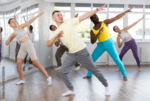 European man conducts lesson for multinational people company, teaches men and women to move aesthetically to beat of music, control their bodies