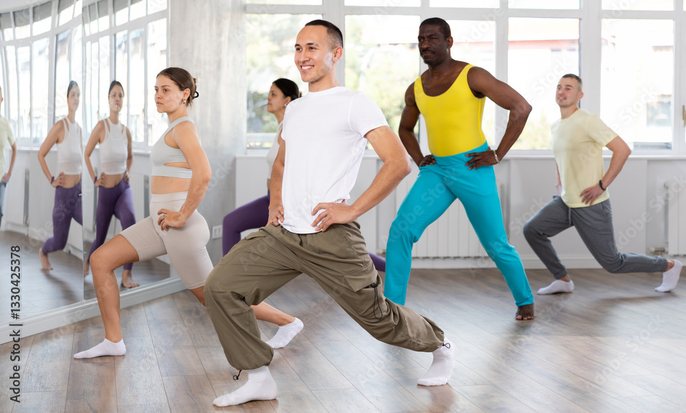 Obraz premium Group of multicultural men and women doing warm-ups before dance class in studio