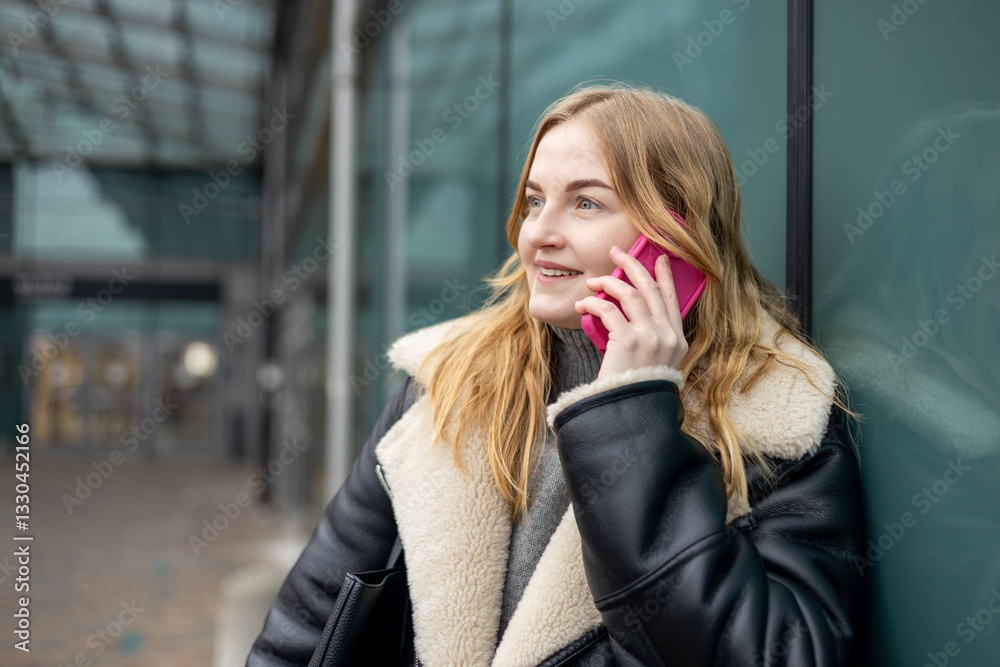 Happy 30s woman talking phone and look happy outdoors. Urban lifestyle concept. Winter time. Beautiful blonde curly woman walking on the modern city street.