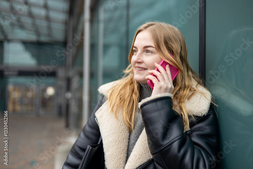 Obraz na płótnie Happy 30s woman talking phone and look happy outdoors. Urban lifestyle concept. Winter time. Beautiful blonde curly woman walking on the modern city street. w salonie
