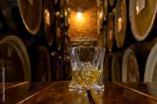 Glass of whisky with ice on old wooden barrel
