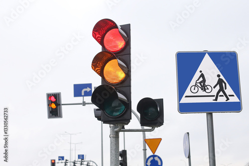 Red and yellow traffic lights at an intersection on a cloudy day. Road safety and transportation control signals. Urban street scene showing a change of lights guiding vehicles and pedestrians.