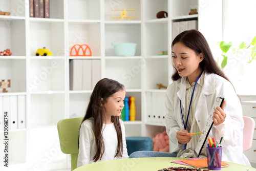 Little girl with speech therapist pronouncing letters in office photo