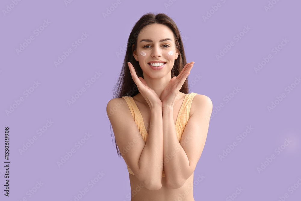 Obraz premium Beautiful young woman with sunscreen cream on her face against lilac background