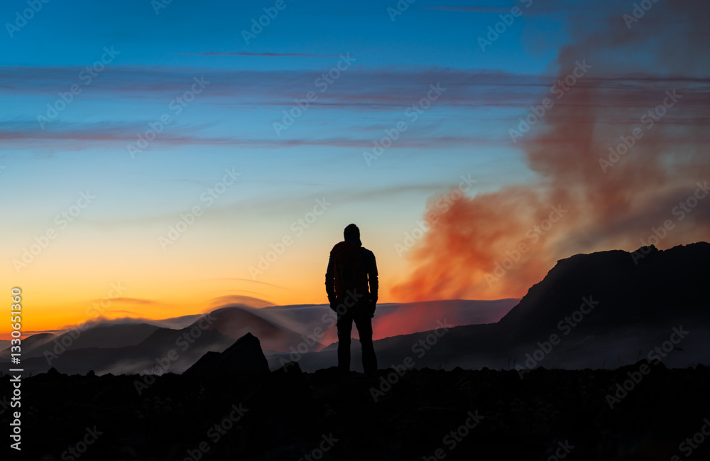 Silhouette observing the smoke from an erupting volcano in Iceland at dawn Silhouette observing the smoke from an erupting volcano in Iceland at dawn