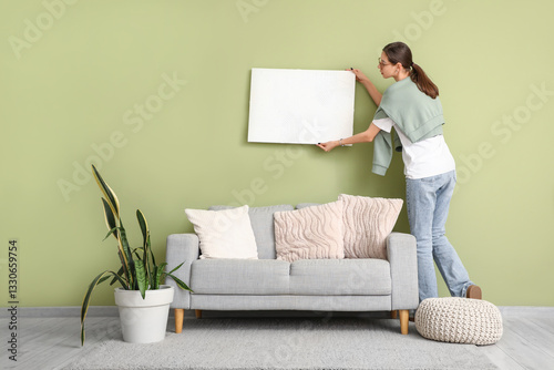 Young woman hanging picture...