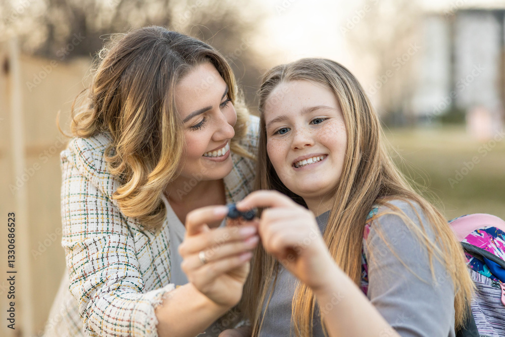 A heartwarming moment between a mother and daughter as they enjoy time together outdoors, sharing a smile and an activity holds bluberries A heartwarming moment between a mother and daughter as they enjoy time together outdoors, sharing a smile and an activity holds bluberries