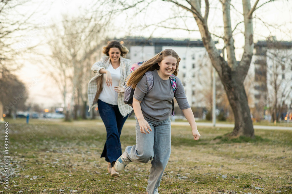 A woman joyfully chases a girl through the park, celebrating their bond with shared laughter and playfulness. A woman joyfully chases a girl through the park, celebrating their bond with shared laughter and playfulness.