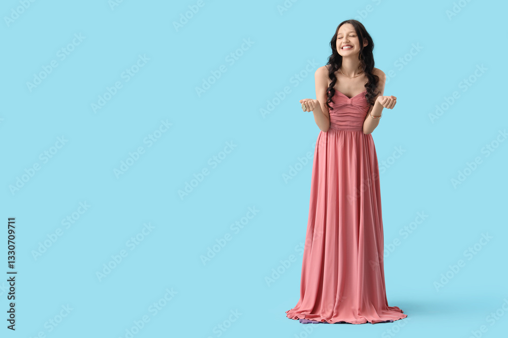 Beautiful happy teenage girl in stylish pink prom dress on blue background Beautiful happy teenage girl in stylish pink prom dress on blue background
