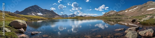 Scenic Panoramic View of Serene Lake Surrounded by Majestic Mountains on a Bright Sunny Day with Cloud Reflections in Clear Blue Waters
