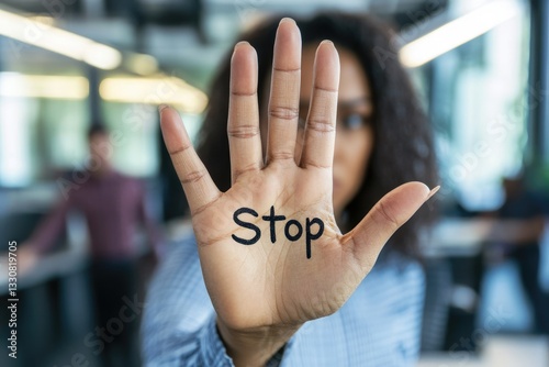 Protective stance: a woman in office with her arm outstretched holding says stop, symbolizing resistance, boundaries, and awareness, addressing the concept of harassment at work with determination.