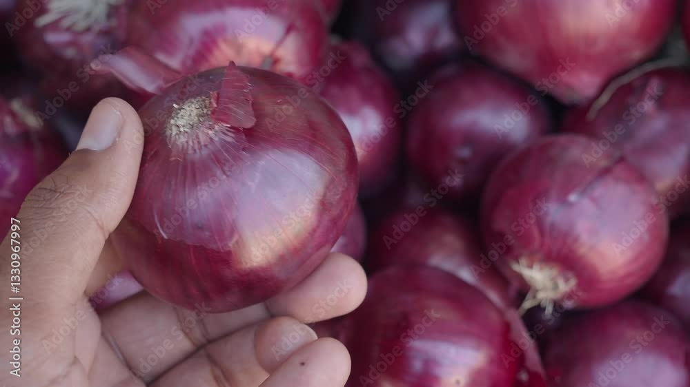 Hand holding red onion among fresh vegetables at market
