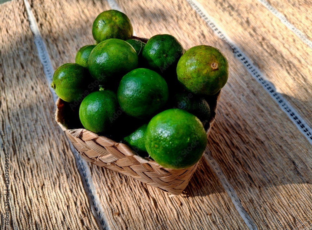 Fresh limes in a woven basket on textured background Fresh limes in a woven basket on textured background