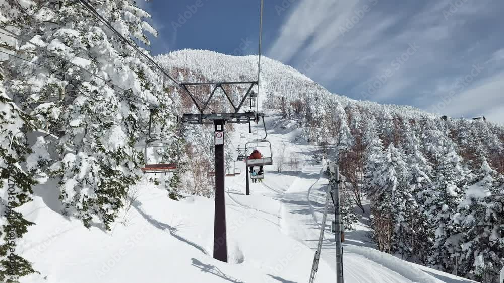 POV ski chairlift through snow covered forest with blue sky. Translation reads POV ski chairlift through snow covered forest with blue sky. Translation reads