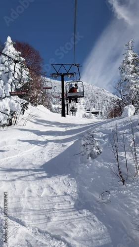 POV ski chairlift through snow covered forest. Vertical handheld shot