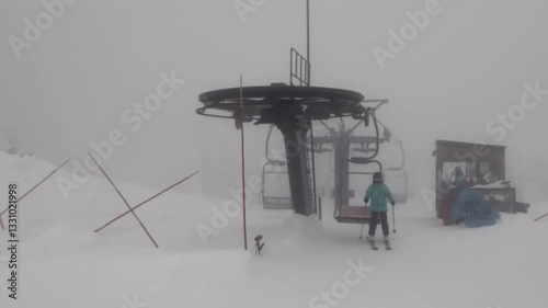 Ski chairlift through fog and low visibility on a mountain peak. Handheld shot