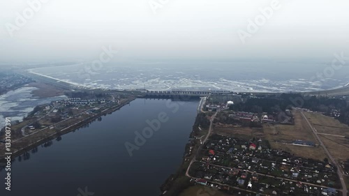 A hydroelectric power station dam, river, and residential area in early spring, aerial view