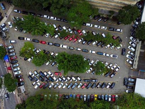 Canvas-taulu An intricate aerial view of a packed parking lot, where rows of cars create a mesmerizing pattern among patches of greenery