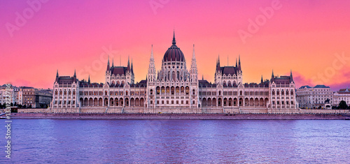 Hungarian parliament building reflecting on danube river at sunset with colorful sky photo
