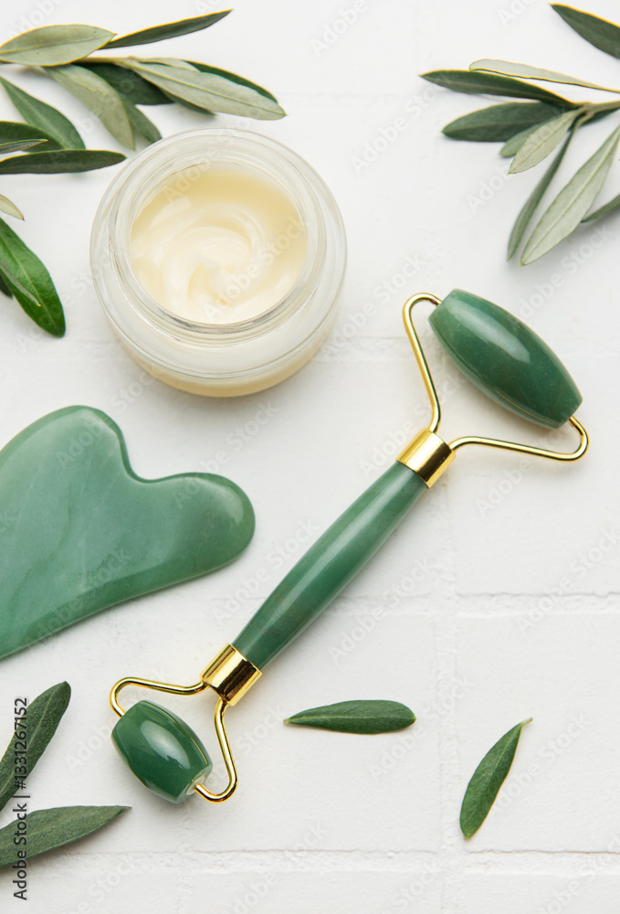 Gua sha stone, face roller and cream promoting skin care and relaxation
