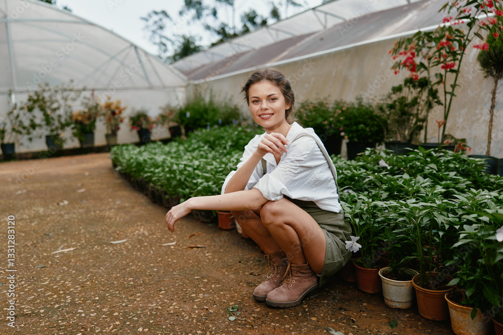 Φωτογραφία Young woman in a greenhouse, wearing casual attire, showcasing a joyful expressi