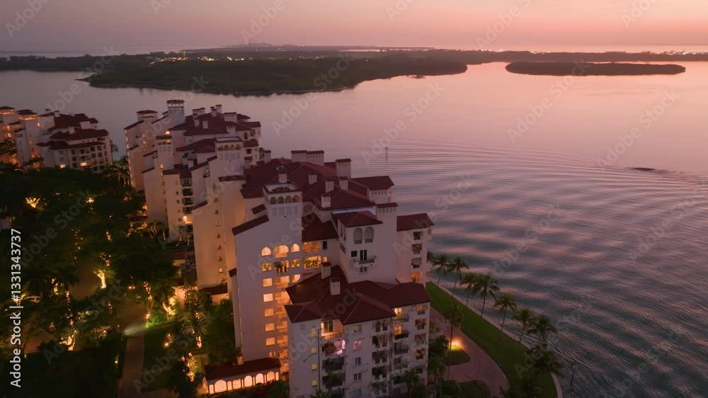 Here is a stunning aerial view of South Pointe Pier located in Fisher Island, Florida, showcasing the serene, calm waters and vibrant, colorful sunset hues that illuminate the sky beautifully