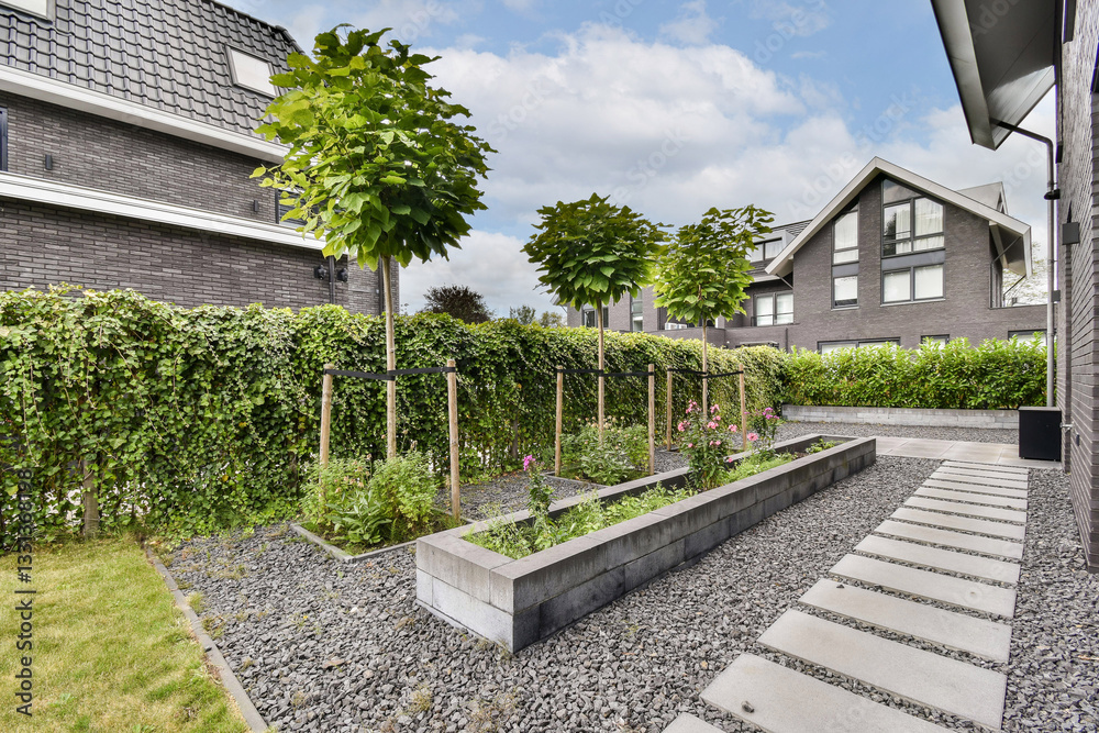 Fototapeta premium A contemporary garden featuring neatly arranged plants, stepping stone pathways, and lush greenery creates a serene outdoor space.
