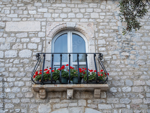 Charming balcony with red geraniums on stone wall