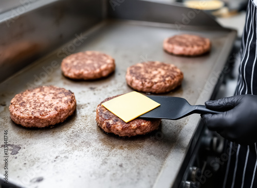 chef preparing a delicious hamburger patty on a griddle with a slice of cheese photo