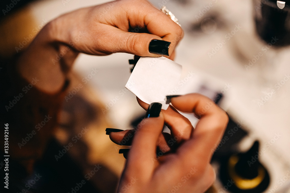 Fototapeta premium Hands holding a blank small piece of paper with manicured nails with black nail polish.